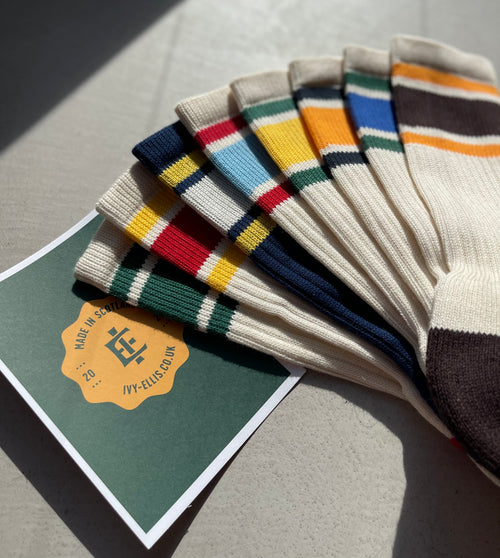 An arrangement of striped retro socks next to an Ivy Ellis postcard